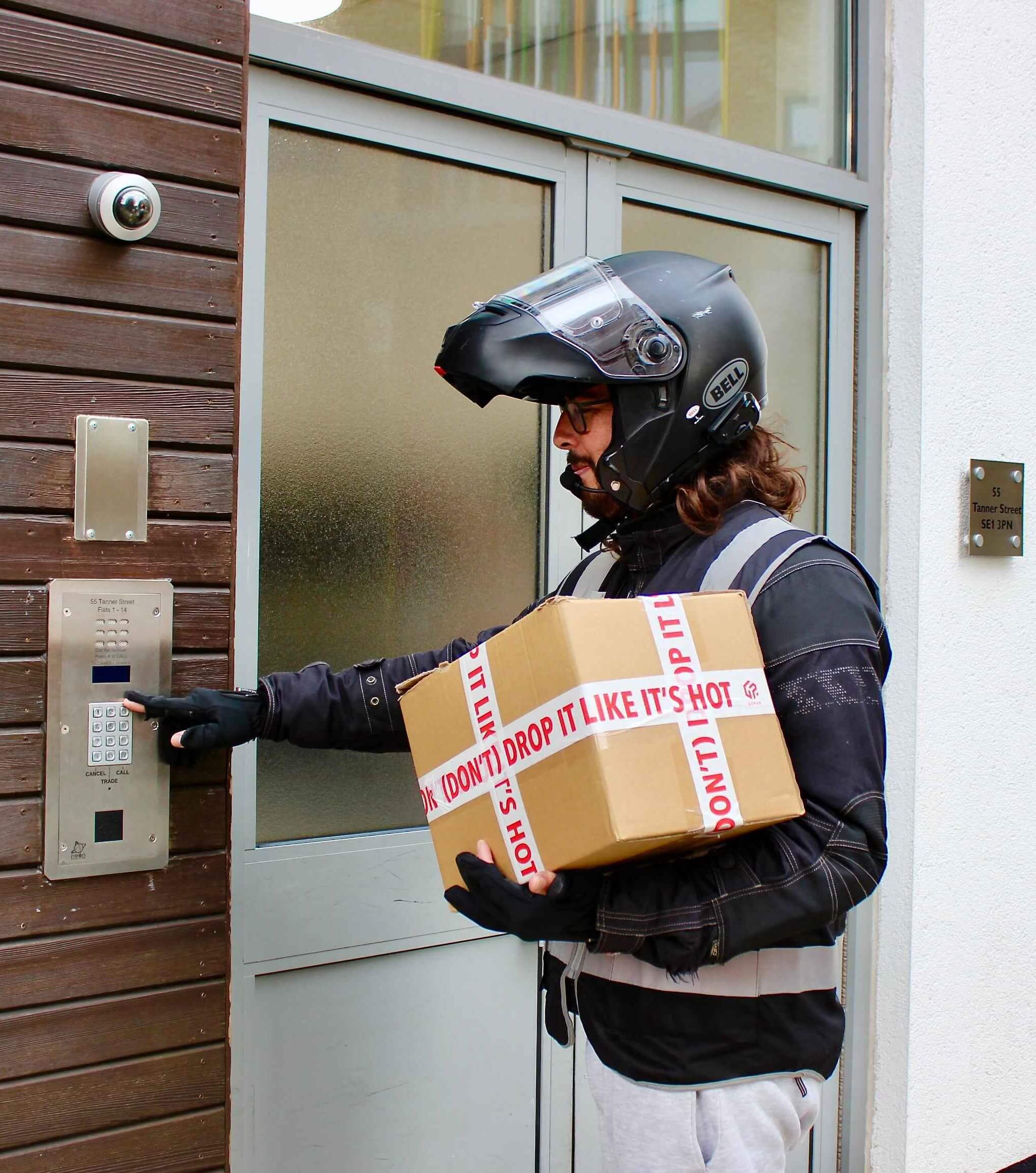 Motorbike courier at a doorway delivering a package
